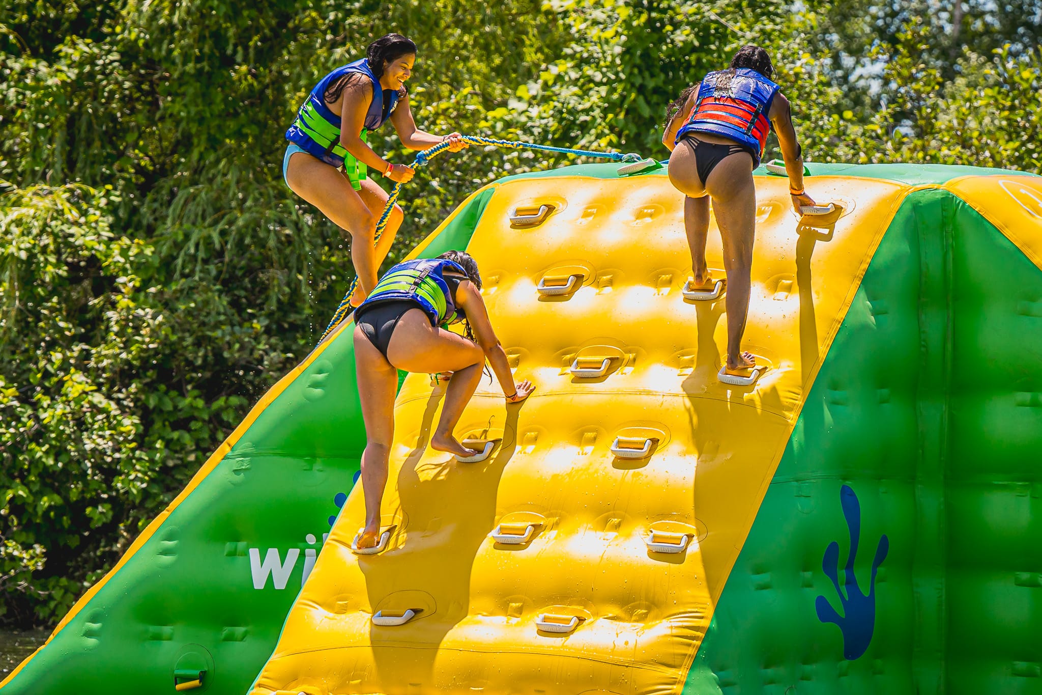 3 personnes qui montent le plus haut sommet du Wipe-Zone, un module gonflable sur le lac