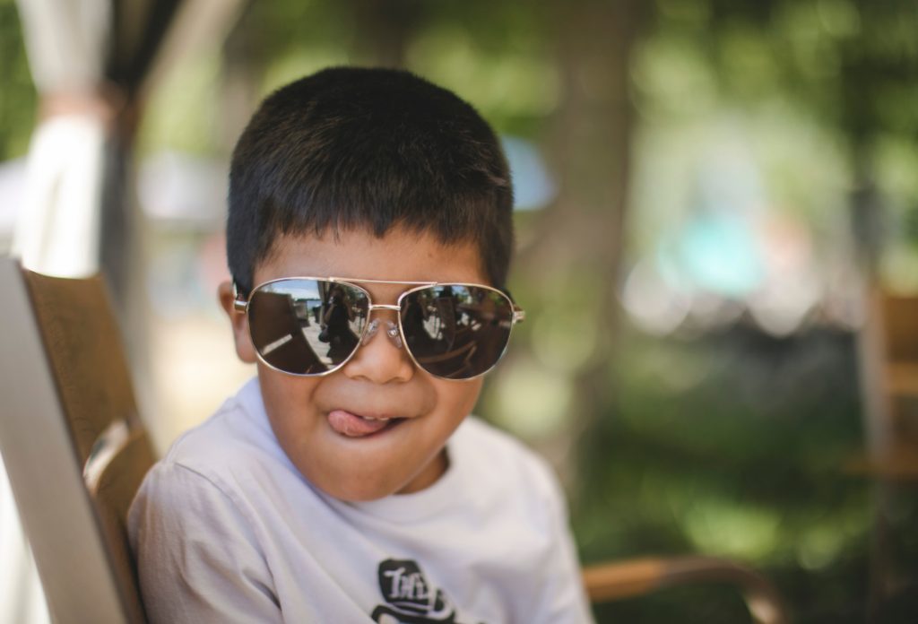 un petit garçon portant des lunettes de soleil qui fait une grimace