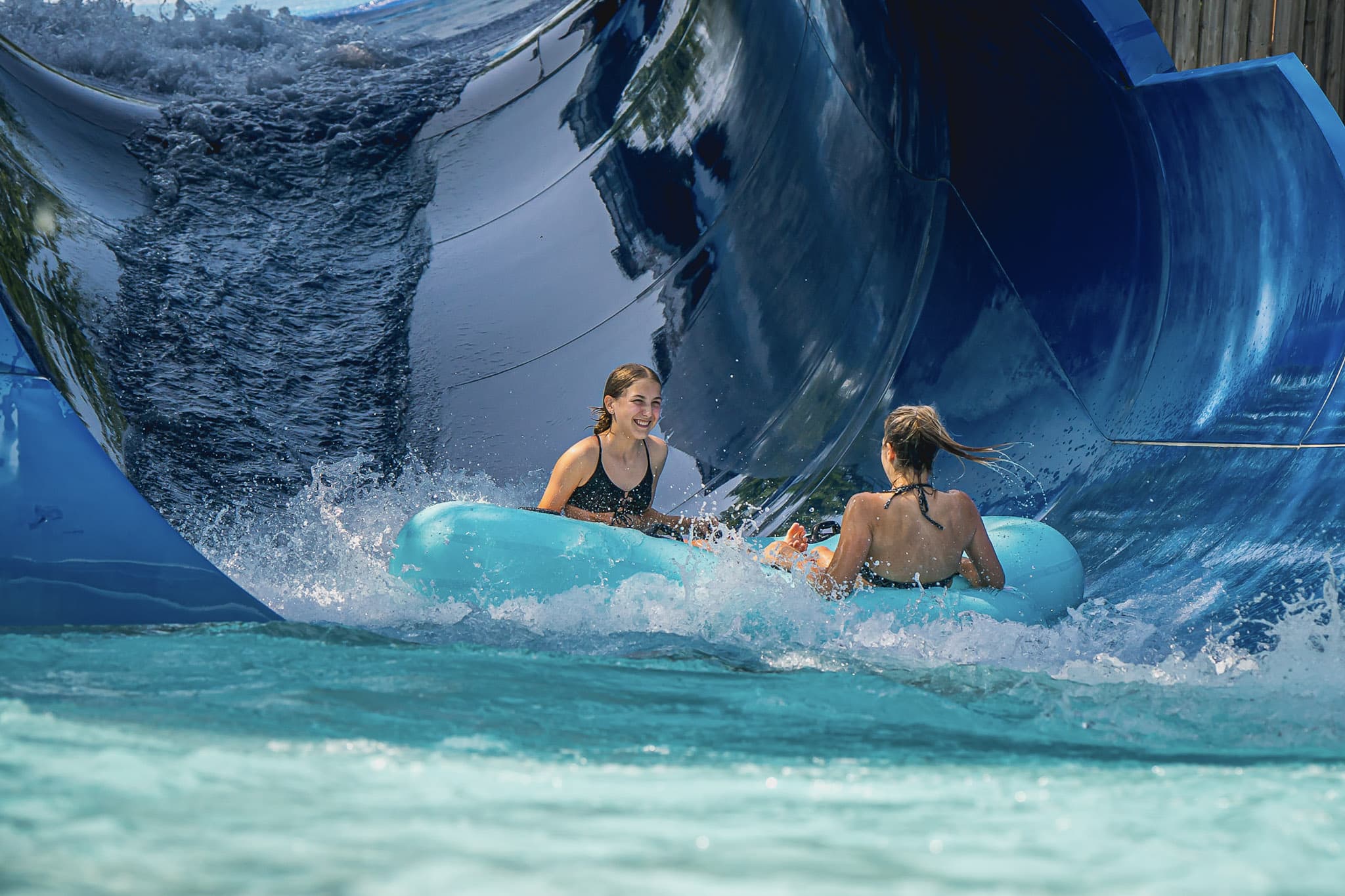 Deux filles qui glissent sur un tube bleu dans une glissade