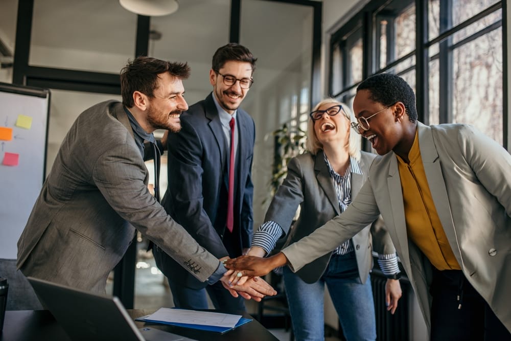 Happy mixed colleagues team people give high five together. Business teamwork results are motivated by business success victory loyalty unity concept, good corporate relations, and team building.
