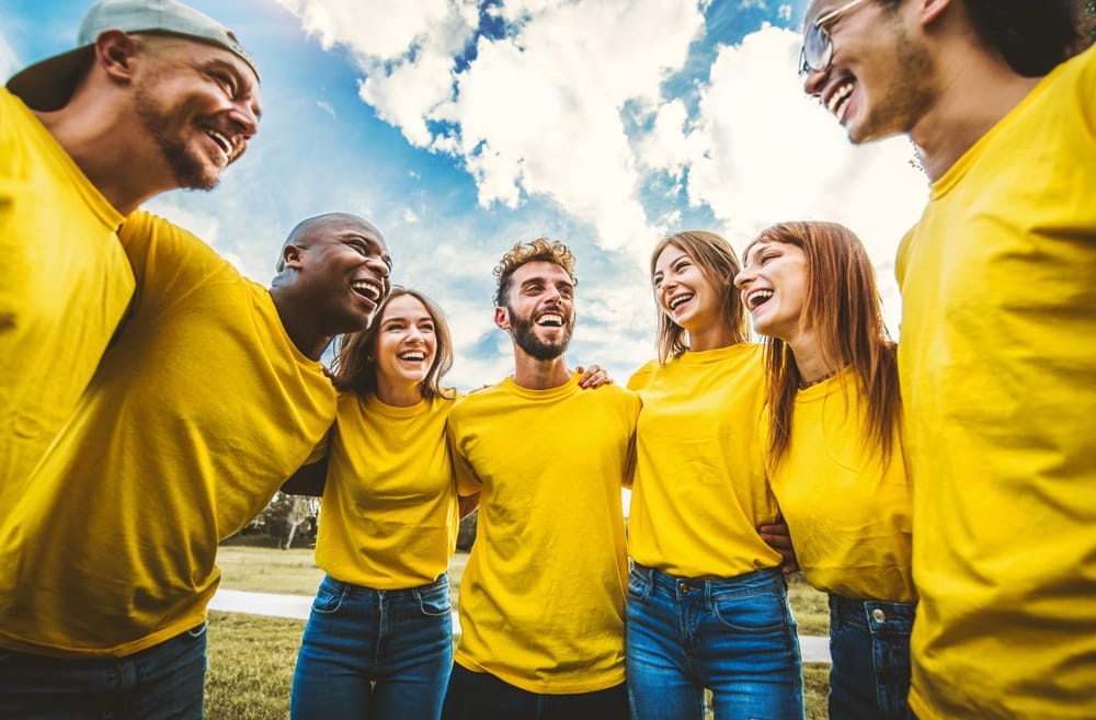 Young people laughing together outside - Team building concept with guys and girls hugging together outdoors - Teamwork