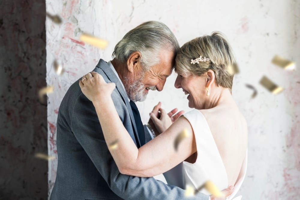 A joyful couple celebrating their wedding. The elderly couple, a Caucasian couple share a tender moment, surrounded by confetti, embodying love and happiness on their special wedding day.